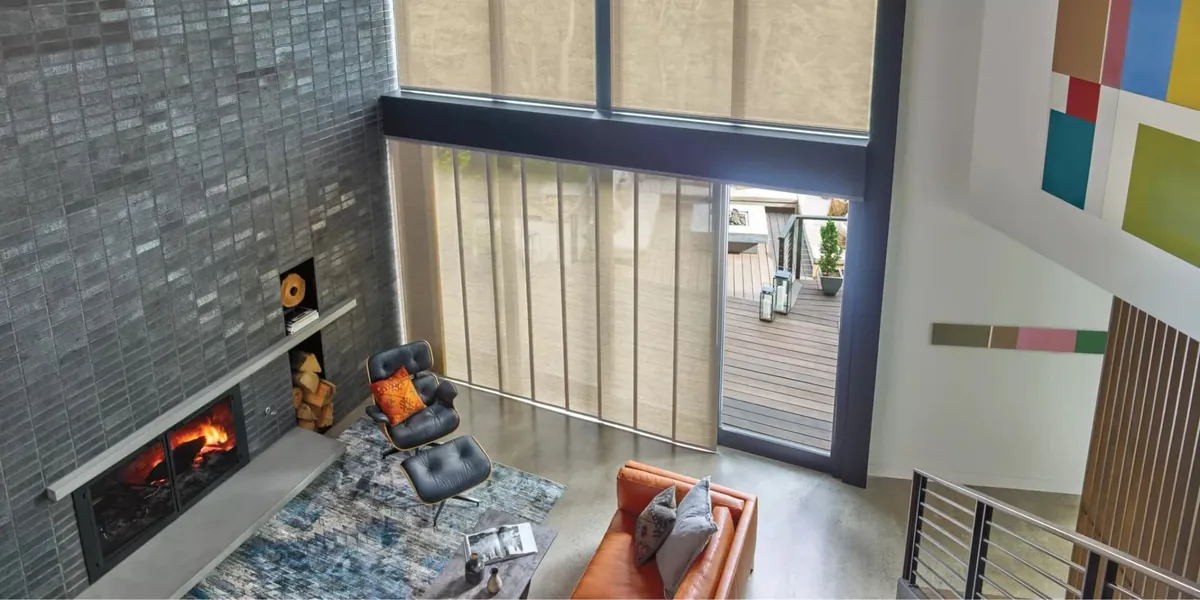 Tan gliding fabric panels on a tall sliding door, seen from above in a living room with a fireplace and leather lounge chair