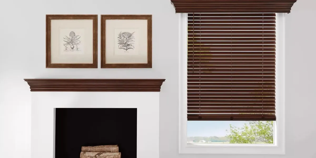 Dark brown wood blinds with a matching cornice on a window beside a white fireplace with a wood mantel